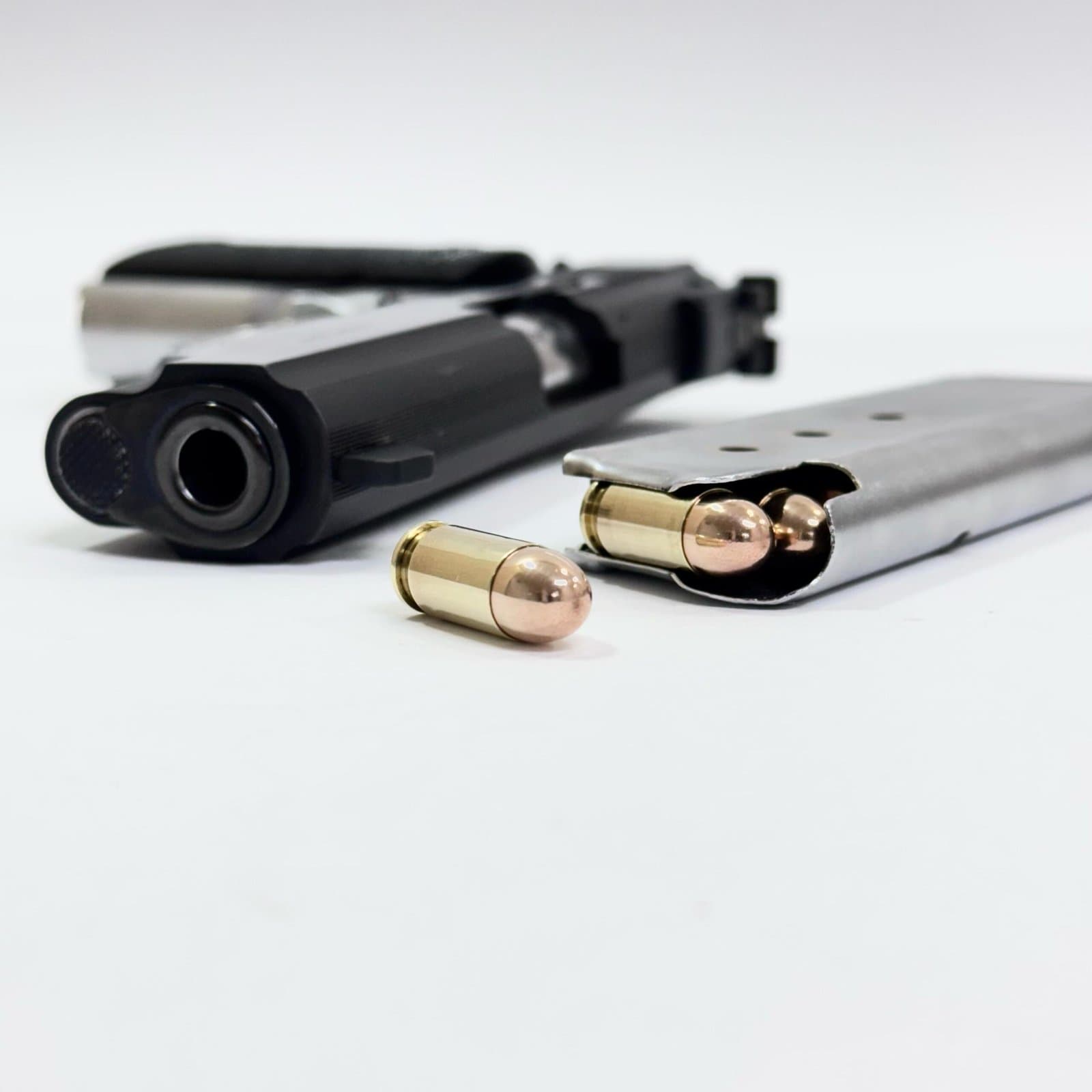 Pistola e cartuchos calibre .380 ACP sobre fundo branco.