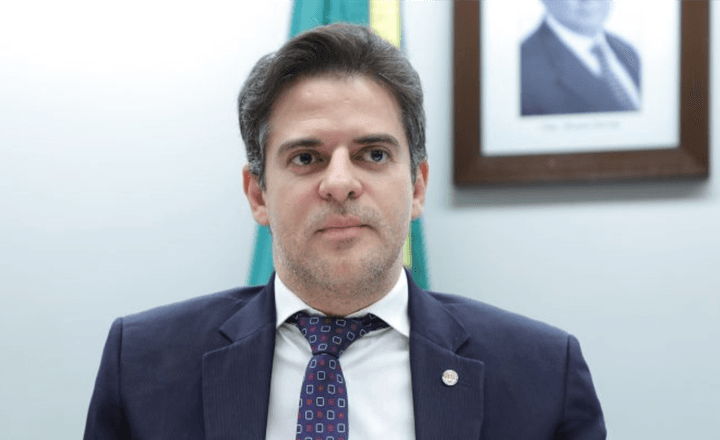 Deputado posa de terno em ambiente institucional.