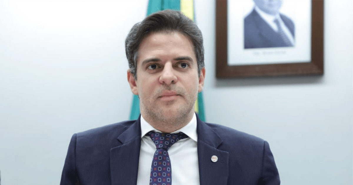 Deputado posa de terno em ambiente institucional.