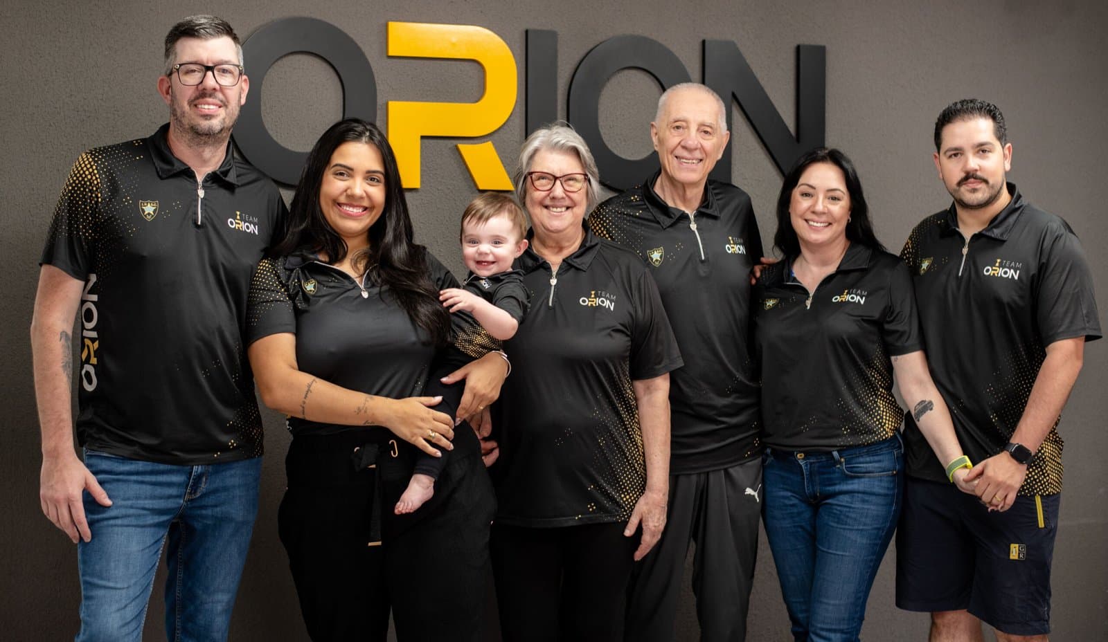 Equipe do Clube de Tiro Orion posa reunida, incluindo uma criança.