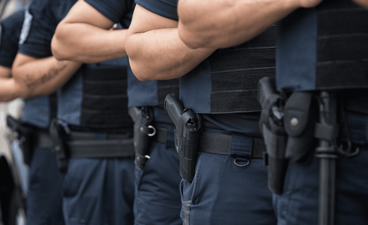 Fileira de policiais armados durante formação em área pública.