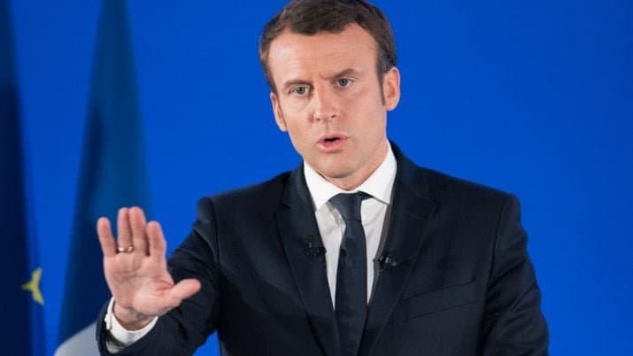 Emmanuel Macron faz pronunciamento diante de fundo azul.