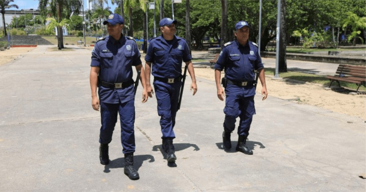 Três guardas municipais caminham em uma praça pública do Recife.