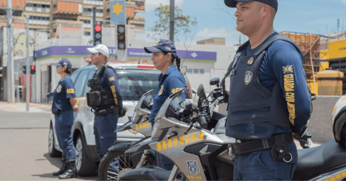 Guardas civis municipais trabalham junto a motocicletas em uma via urbana.