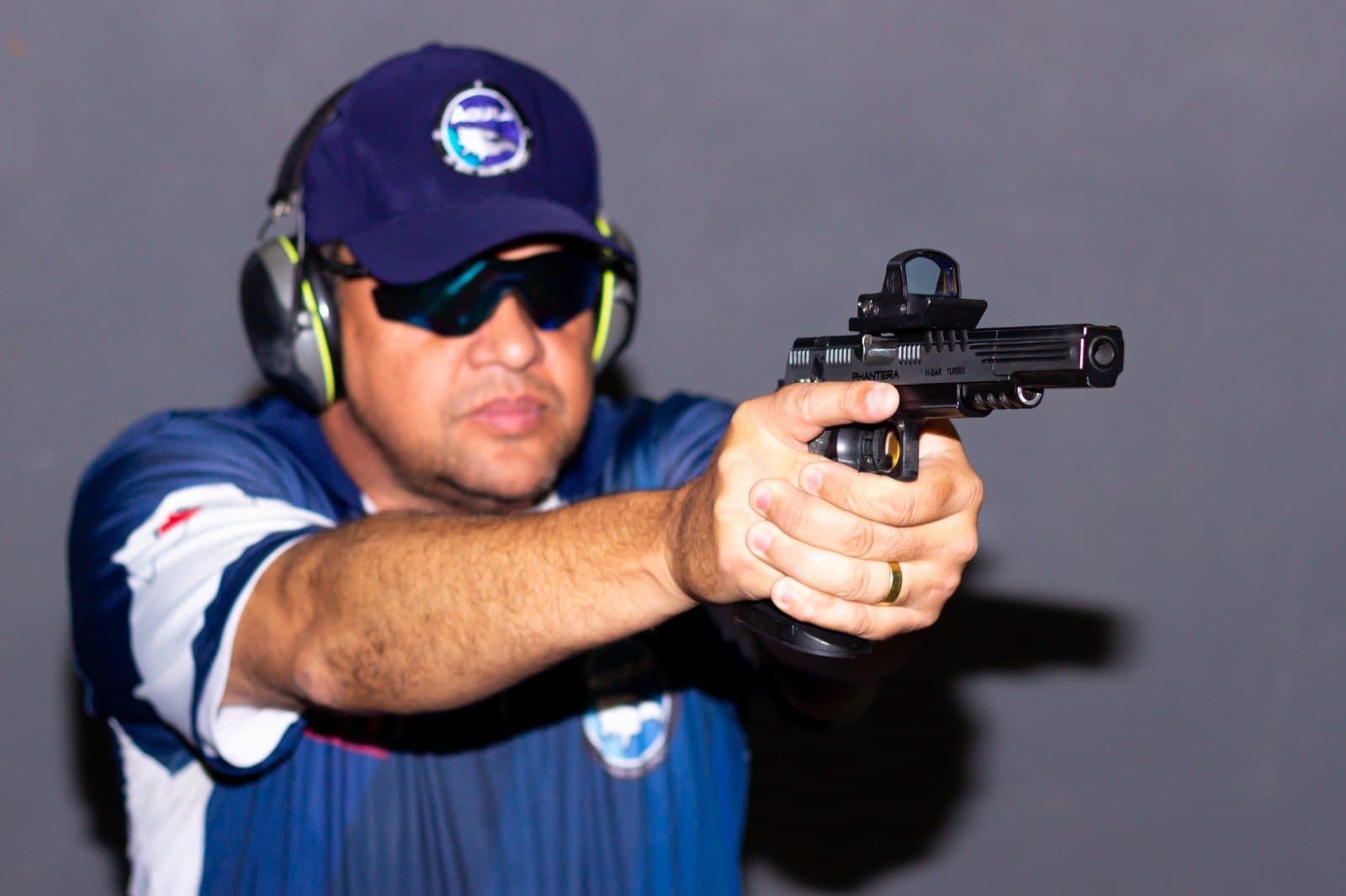 Leandro Boaventura pratica tiro com pistola equipada com mira.