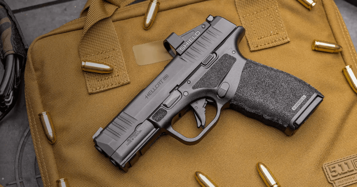 Pistola Hellcat Pro e cartuchos sobre uma bolsa tática marrom.