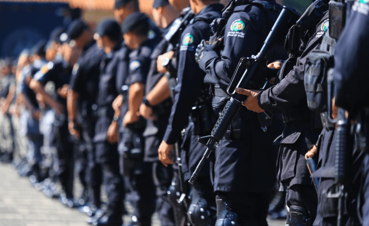 Policiais armados permanecem em formação.