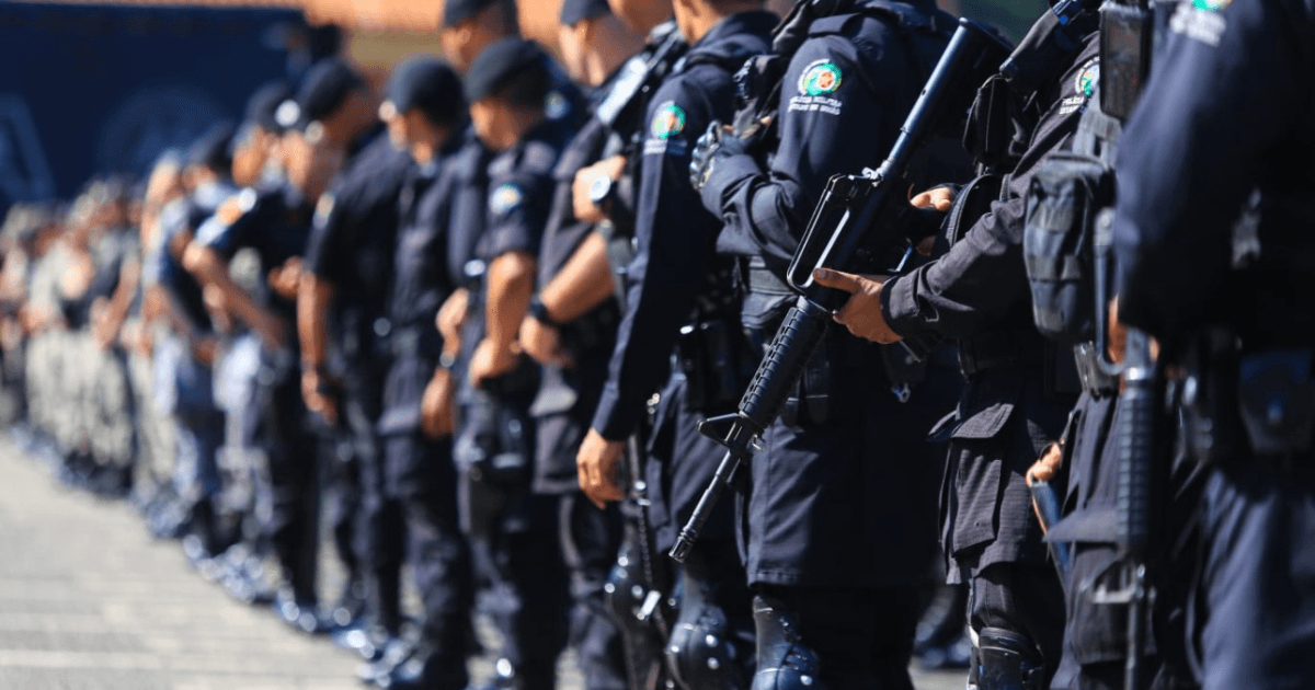 Policiais armados permanecem em formação.