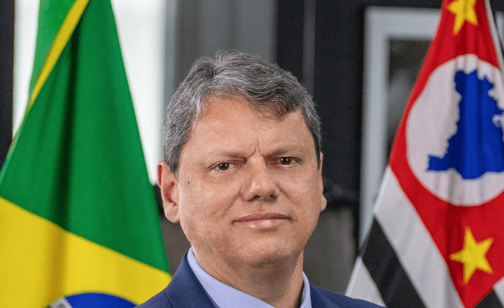 Governador Tarcísio de Freitas posa diante das bandeiras do Brasil e de São Paulo.