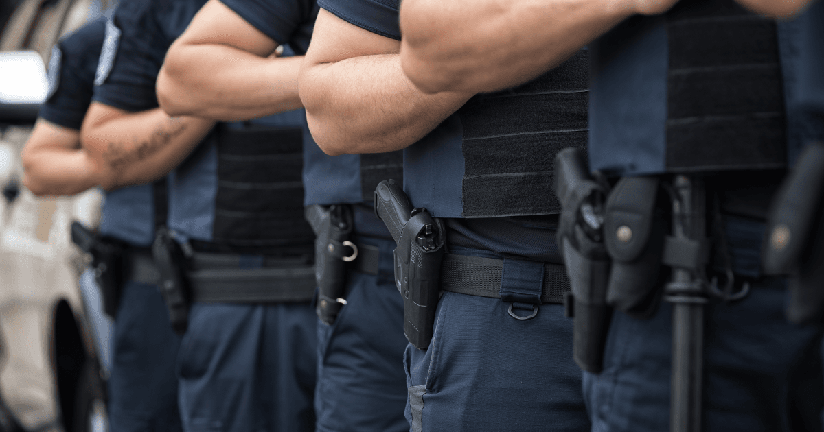 Fileira de policiais armados durante formação em área pública.