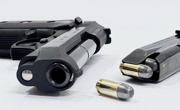 Duas pistolas e munição sobre fundo branco.