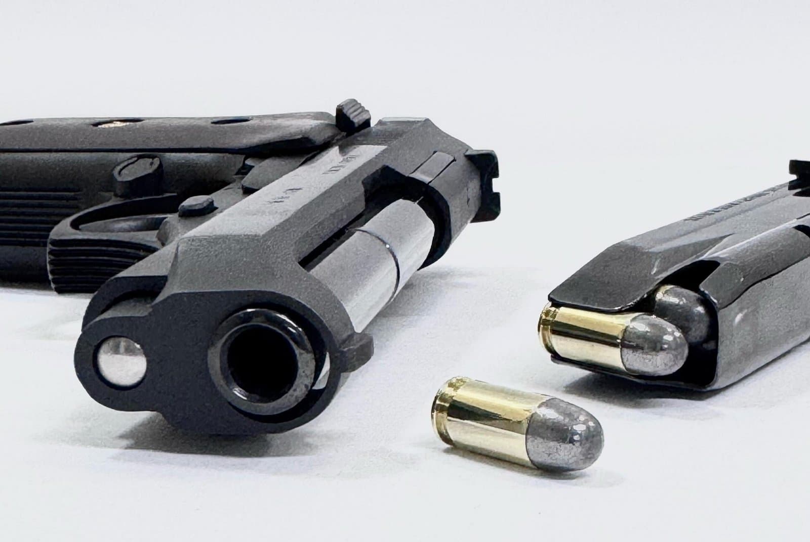 Duas pistolas e munição sobre fundo branco.
