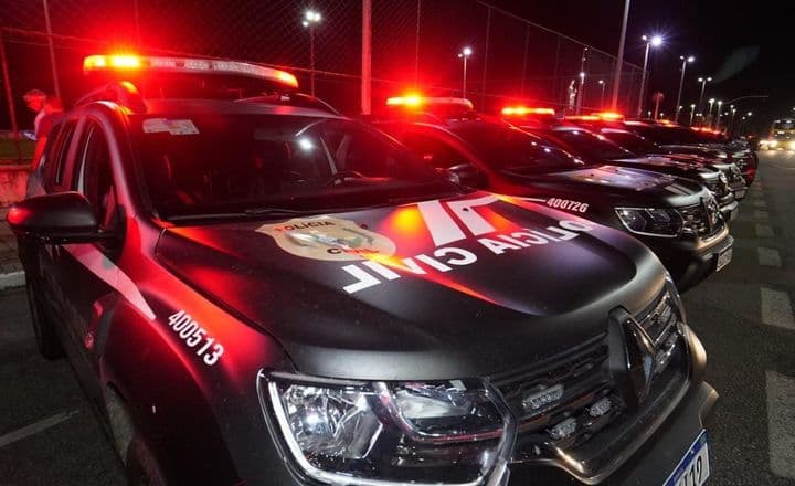 Viaturas da Polícia Civil com luzes vermelhas acesas durante operação noturna.