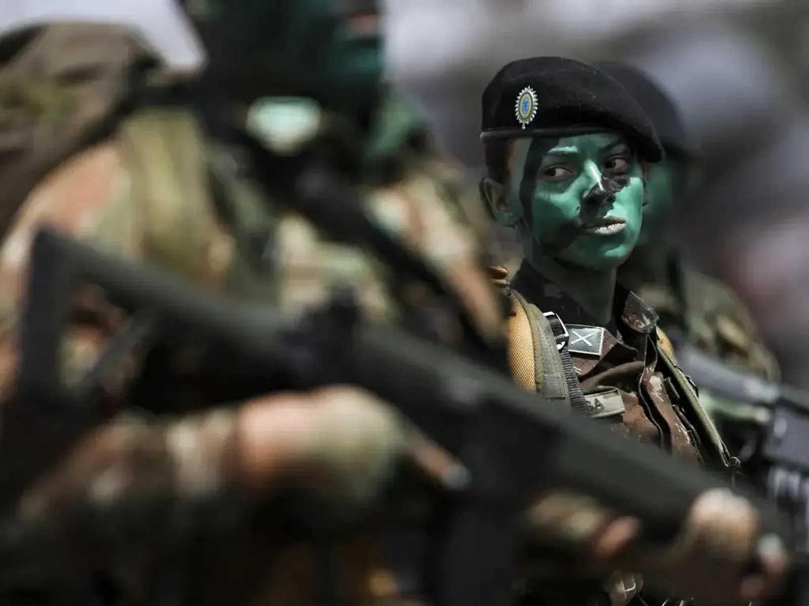 Militar mulher usando boina e camuflagem durante formação.