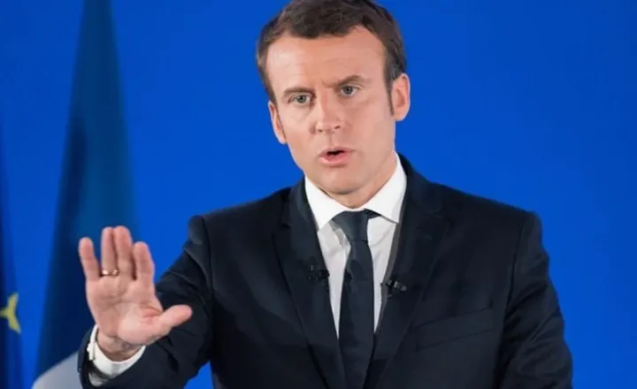 Emmanuel Macron faz pronunciamento diante de fundo azul.
