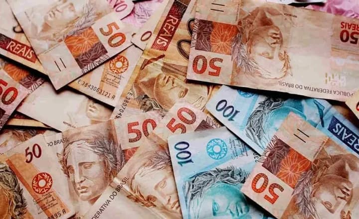 Cédulas de real espalhadas sobre uma superfície.