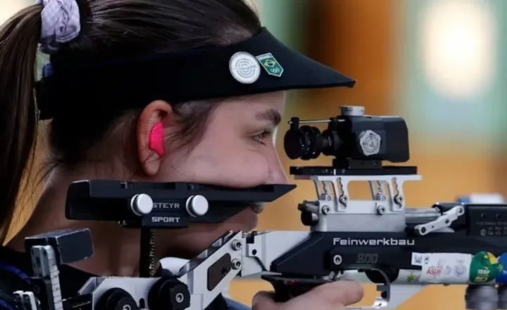 Atleta brasileira mira uma carabina em prova olímpica.