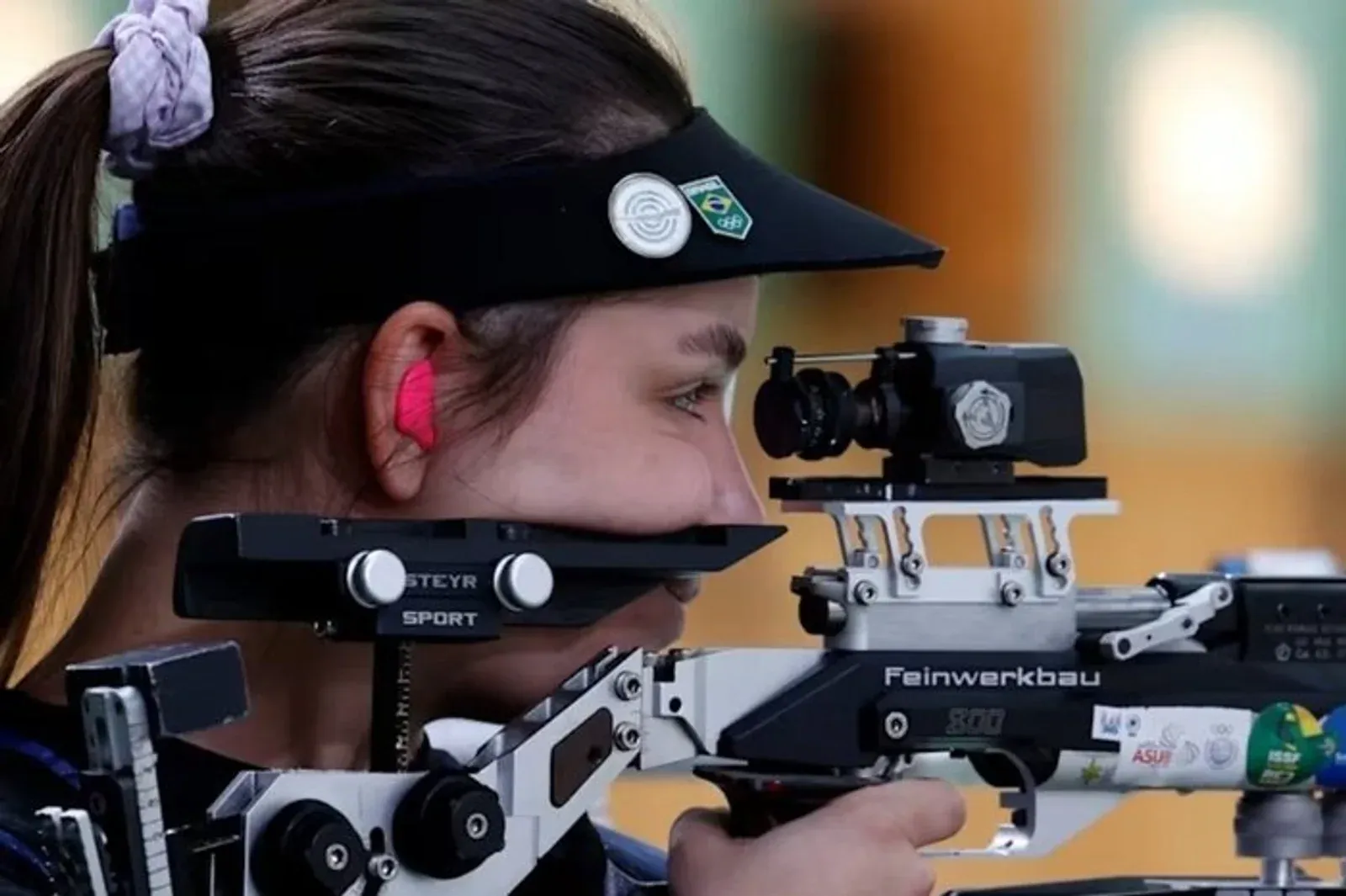 Atleta brasileira mira uma carabina em prova olímpica.