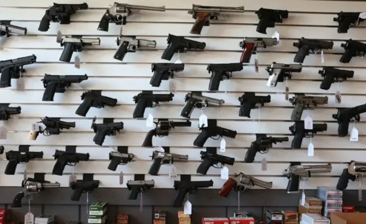 Diversas pistolas expostas em painel de loja de armas.