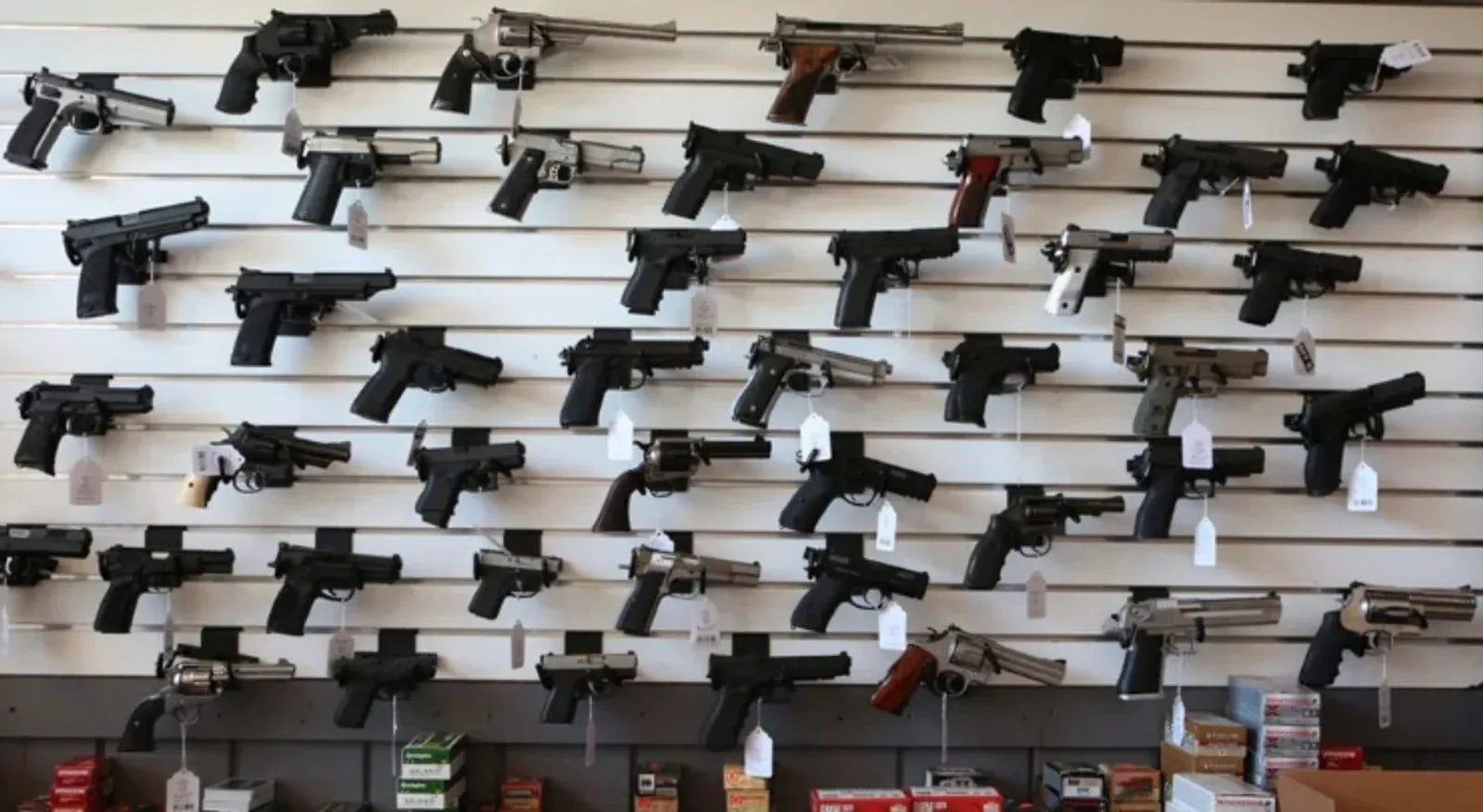 Diversas pistolas expostas em painel de loja de armas.