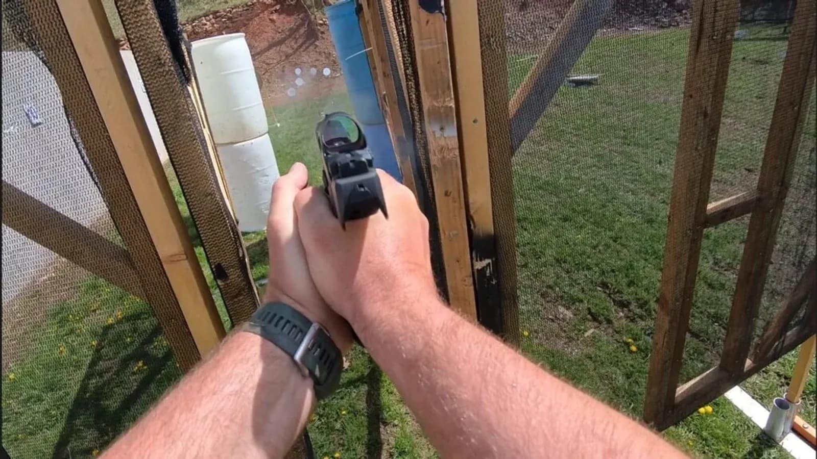 Atirador aponta uma pistola equipada com mira em uma pista de competição.