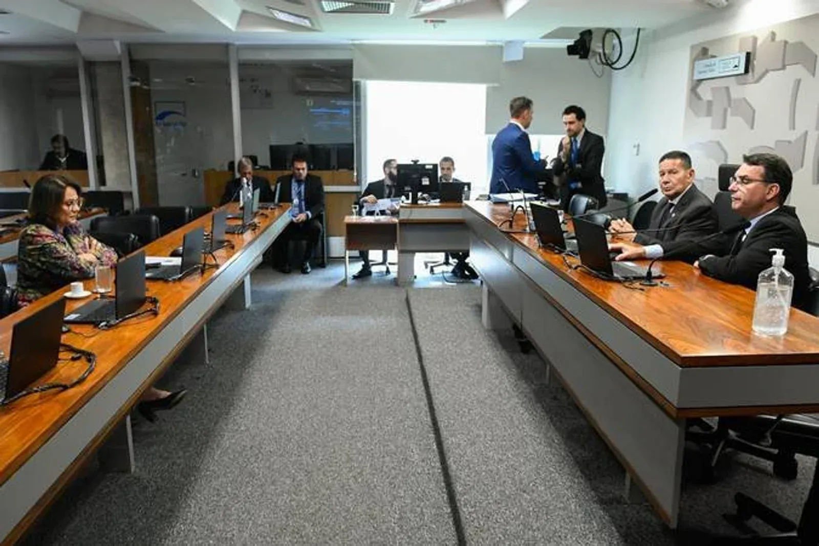 Reunião de comissão com parlamentares e representantes sentados à mesa.