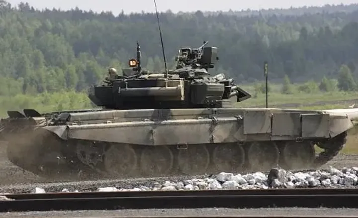 Tanque militar percorre terreno aberto durante exercício.