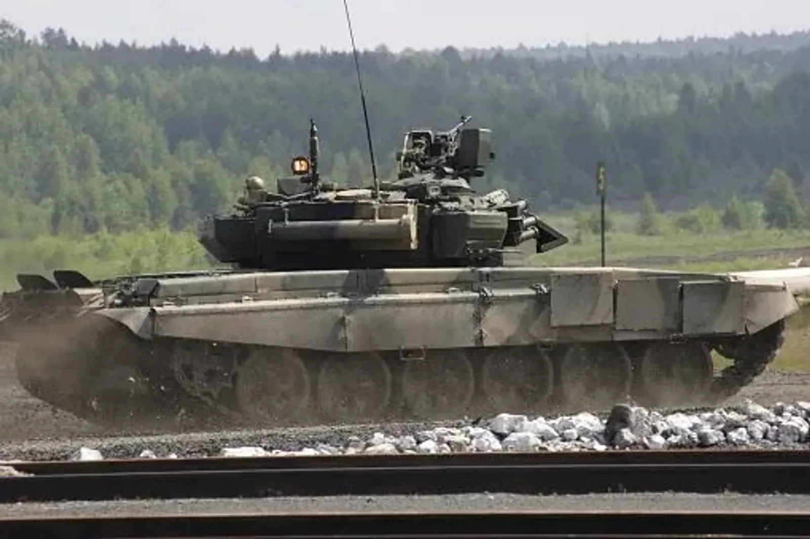 Tanque militar percorre terreno aberto durante exercício.