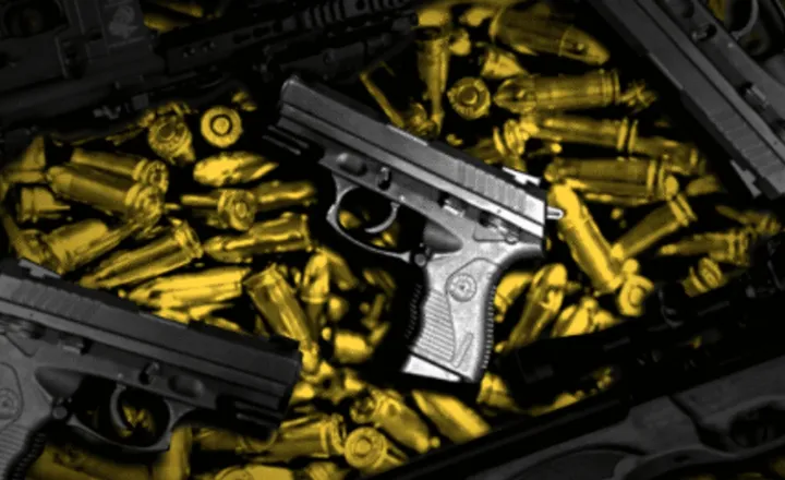 Duas pistolas pretas sobre uma grande quantidade de cartuchos dourados.