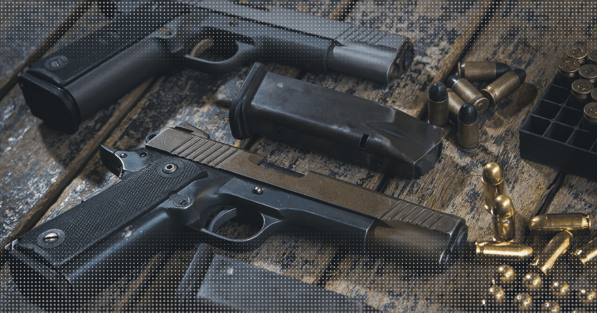 Duas pistolas, carregadores e cartuchos sobre uma bancada de madeira.