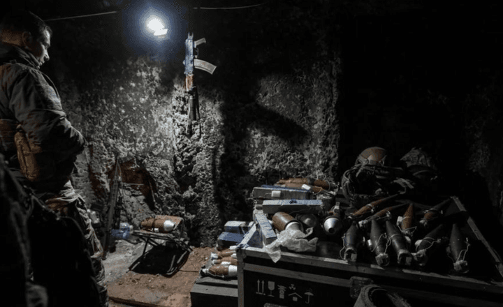 Militares trabalham com armamentos em uma posição escura de combate.