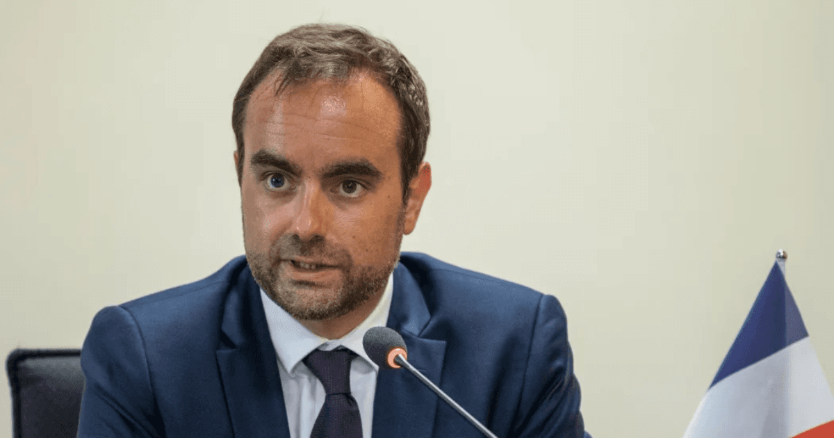 Homem de terno fala ao microfone durante uma reunião oficial.