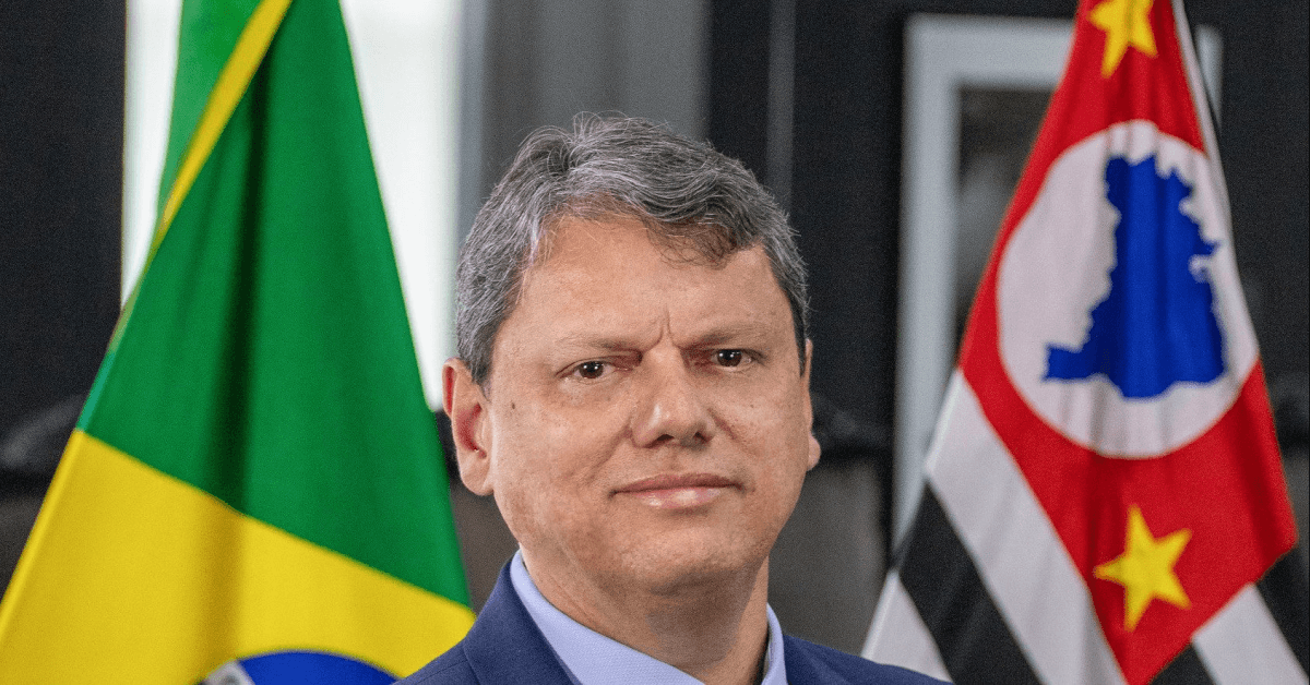 Governador Tarcísio de Freitas posa diante das bandeiras do Brasil e de São Paulo.